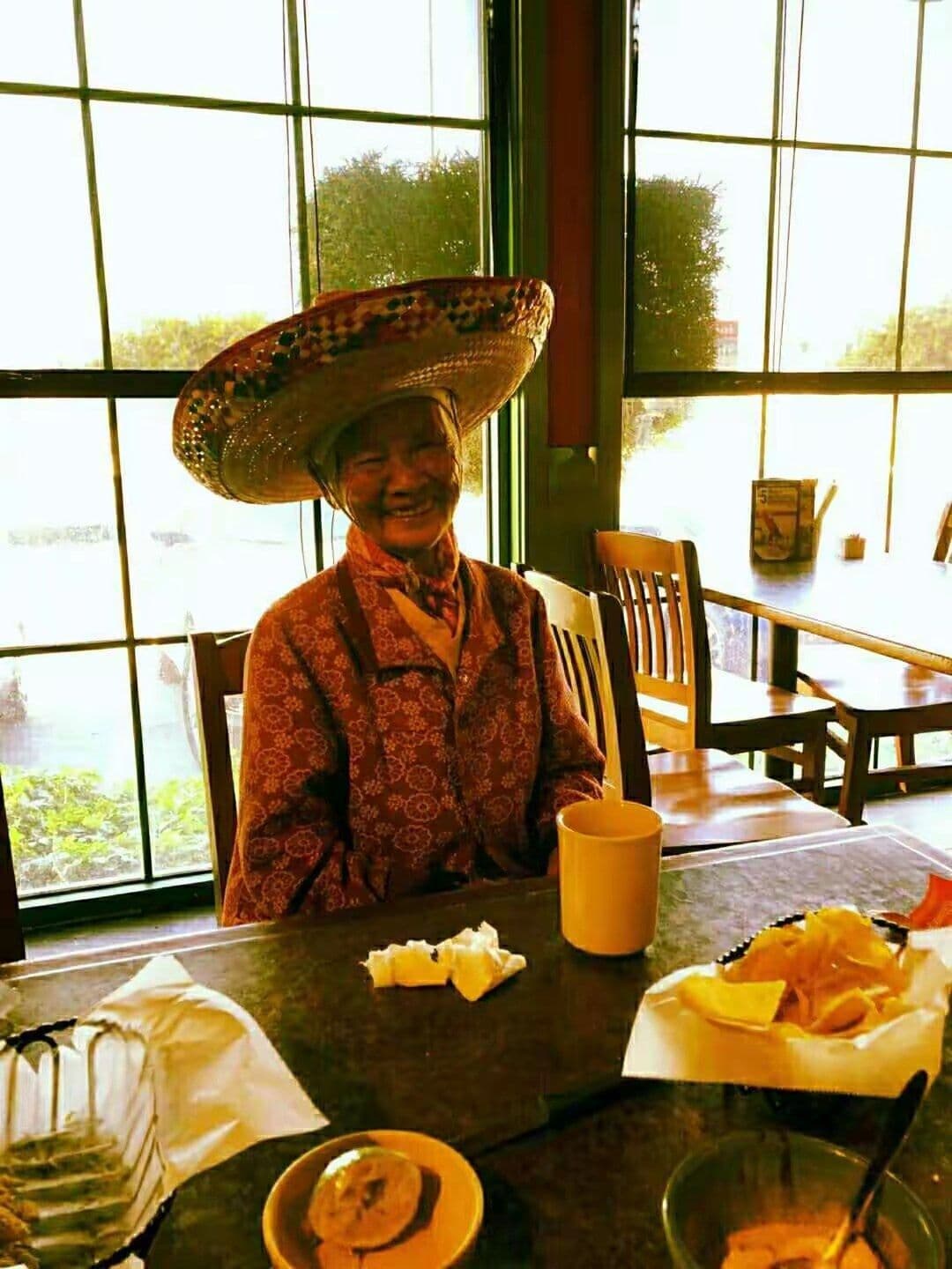 Our mother, 99, laughing in a big sombrero at a restaurant table.